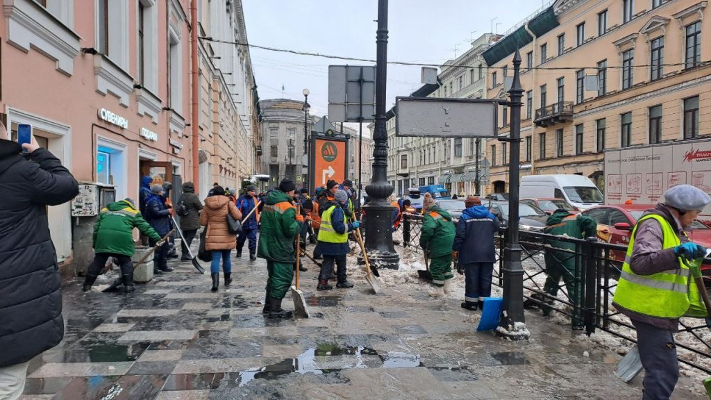 На Большой Морской толпа дворников рубит гололед на тротуаре