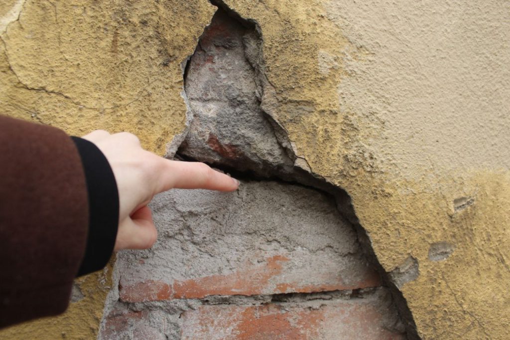 Палец залезает в дыры в стенах домов на Флигельной